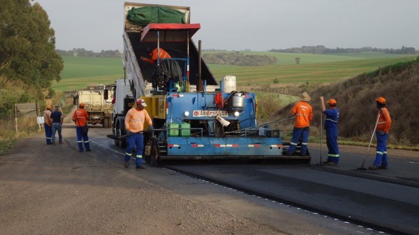 A foto mostra a rodovia ERS-324, no trecho entre Natalino e Lagoa Bonita. Na rodovia, está um caminhão azul e ao redor dele homens trabalhando na recuperação da pista da rodovia.